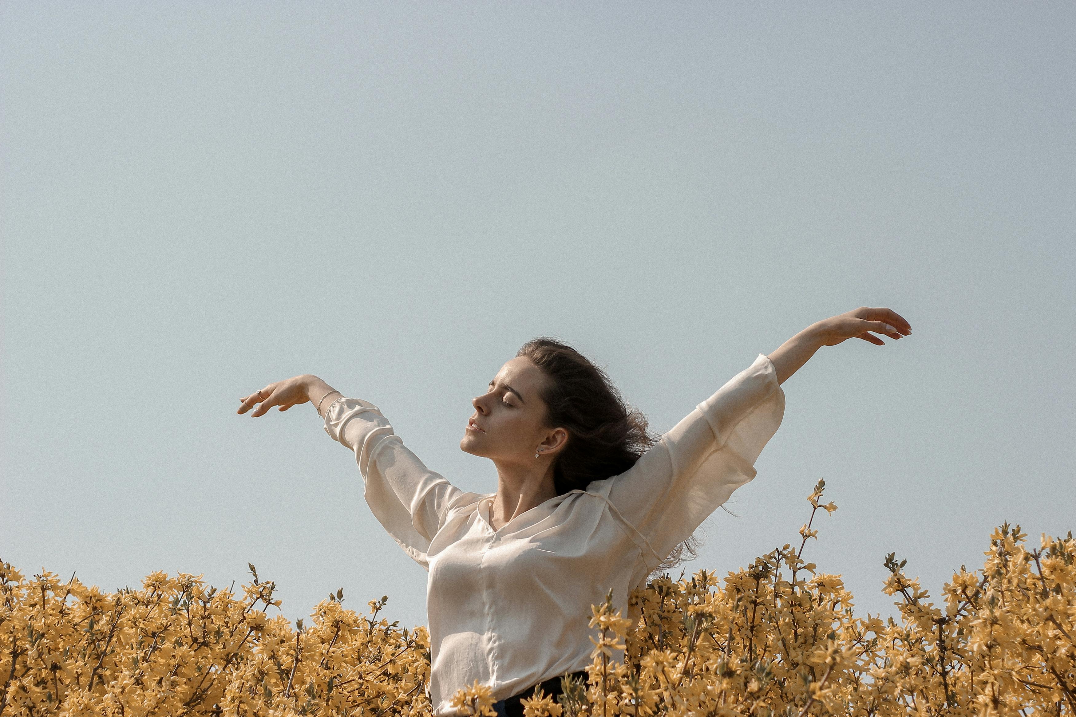 girl walking through a field with her arms raiseded