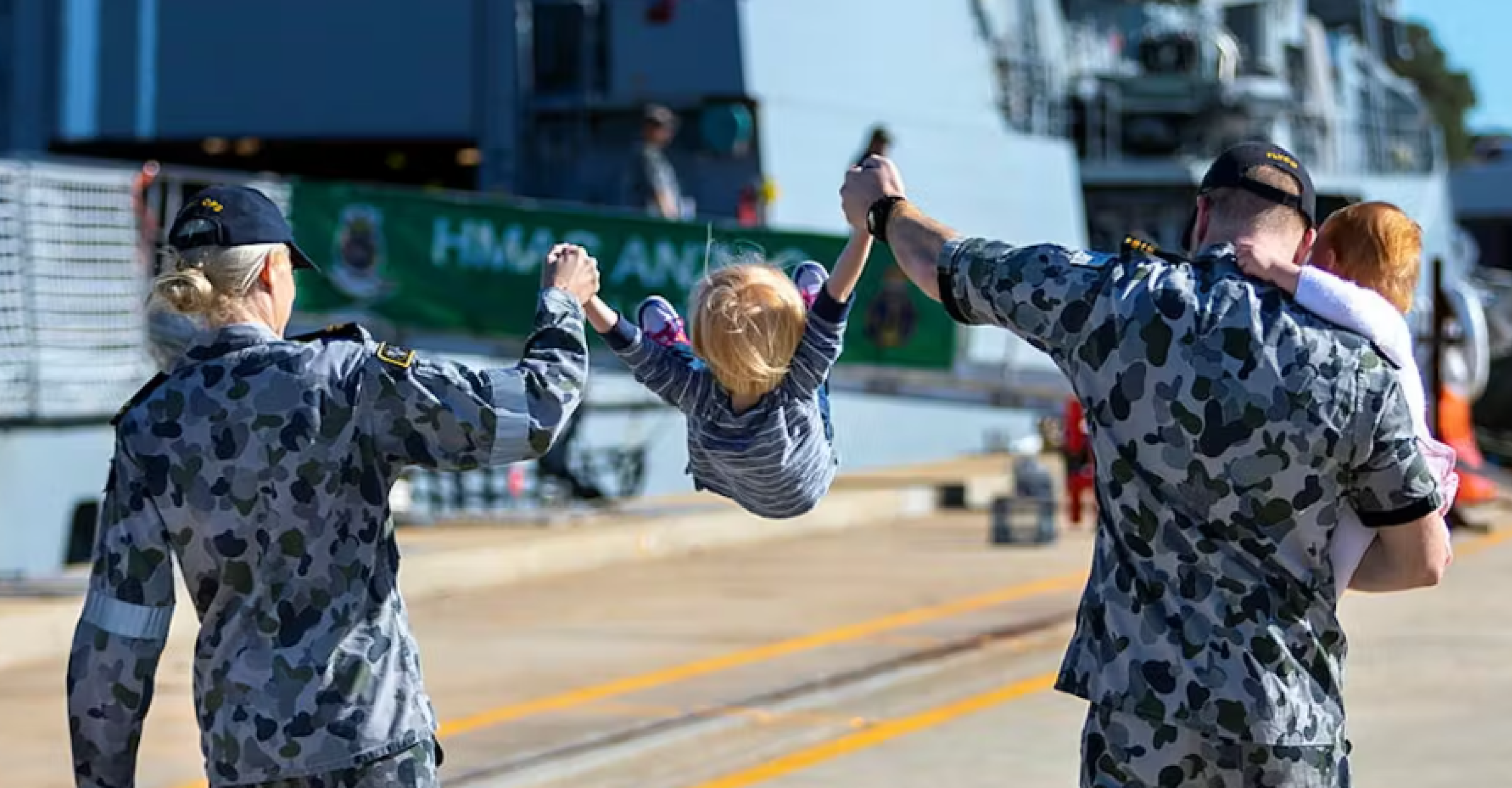 Navy family mum dad and two small children on the docks where HMAS ANZAC is moaredd
