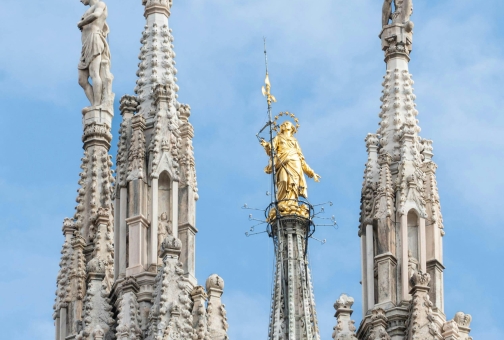 gold saint statue on top of a entryway church
